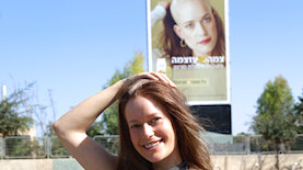 גלי שחר עם שלט חוצות של הקמפיין, צילום: רפי דליוה